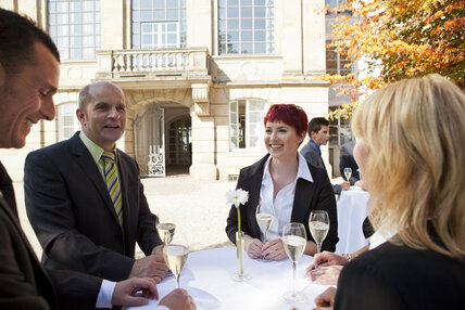 sechs Personen stehen an Stehtischen im hinteren Schlosshof